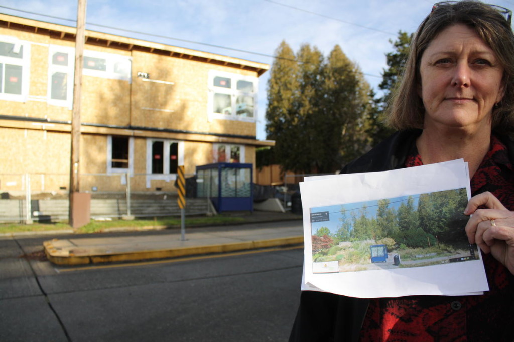 Cass Turnbull stands before a former substation site. She holds a Google Street View image showing the landscaping recently removed to make way for townhomes. 